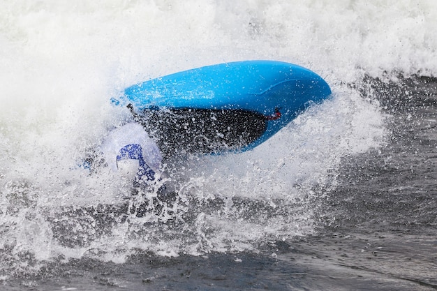 Um caiaque masculino ativo rolando e surfando em águas agitadas