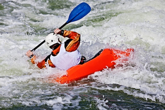 Um caiaque masculino ativo rolando e surfando em águas agitadas