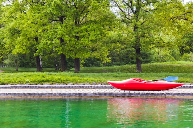 Um caiaque vermelho no cais de madeira em um lago