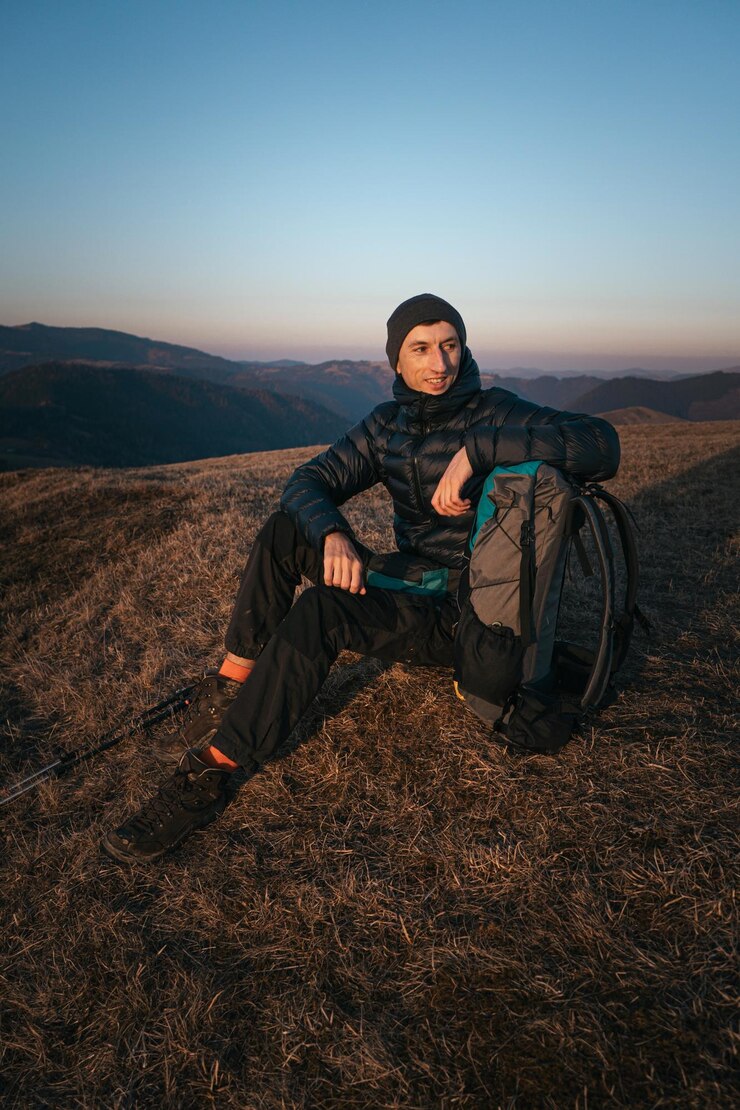 Foto um caminhante descansando no cume da montanha ao pôr-do-sol