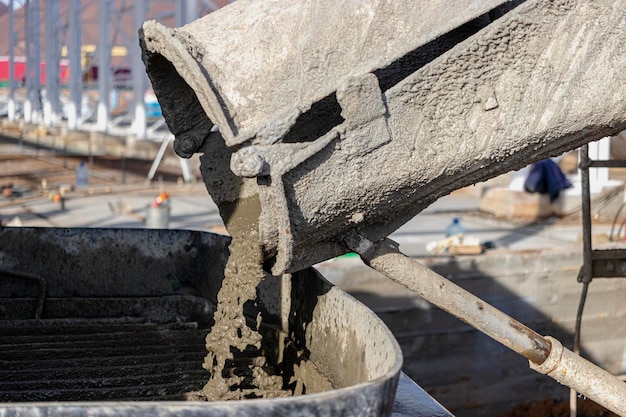 Um caminhão betoneira despeja concreto em uma bomba em um canteiro de obras.