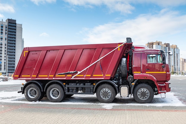 Um caminhão de descarga vermelho em um estacionamento na cidade no inverno