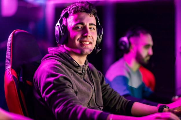 Um campeão de jogos sorrindo para a câmera e jogando videogame