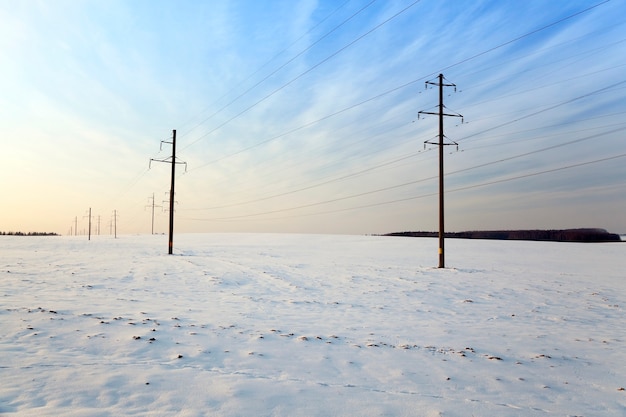 Um campo coberto de neve no inverno. nos postes de energia visíveis. pôr do sol