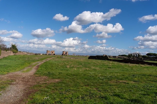 Um campo com uma estrada de terra e alguns edifícios ao fundo