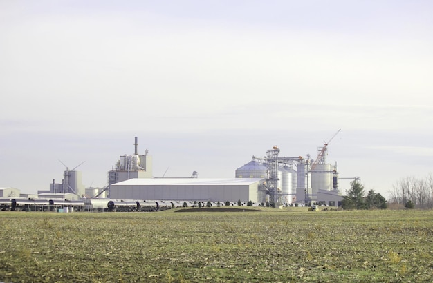 Foto um campo com uma fábrica com um campo no fundo e uma fábrica no fundo