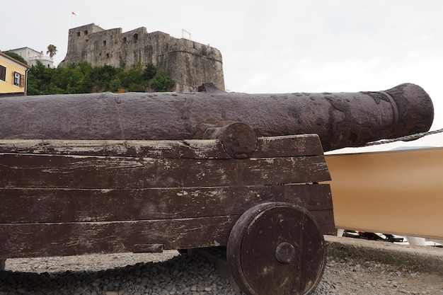 Um canhão um dispositivo de arremesso um tipo de arma de artilharia para disparar em uma trajetória plana, bem como em alvos aéreos e marítimos Canhão antigo de ferro fundido em Herceg Novi Montenegro Artilharia naval Arma costeira