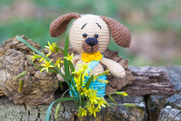 Um cão marrom pequeno em calças azuis. brinquedo de malha, feito à mão, amigurumi