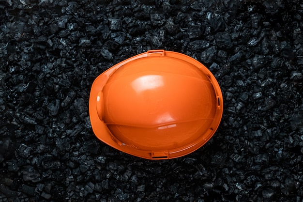 Um capacete laranja de um mineiro encontra-se em uma pilha de carvão, mineração a céu aberto, copie o espaço.