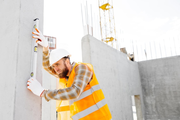 Um capataz construtor e reparador com um capacete protetor verifica a regularidade de uma escada de estrutura de concreto