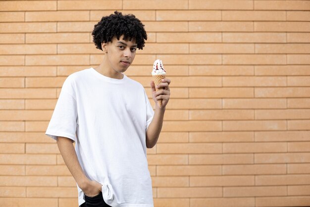 Um cara americano encaracolado confiante segurando uma casquinha de sorvete com a mão na bolsa