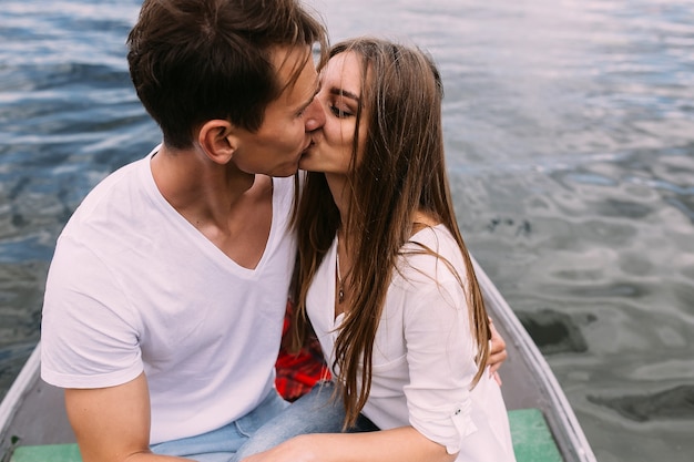 Um cara bonito e uma linda garota descansando em um barco no lago