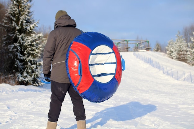 Um cara com um tubo inflável de inverno está parado em uma encosta de neve esqui alpino