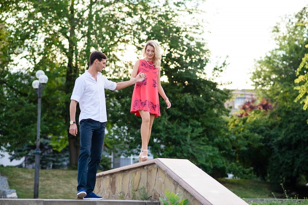 Um cara com uma garota de mãos dadas no parque.