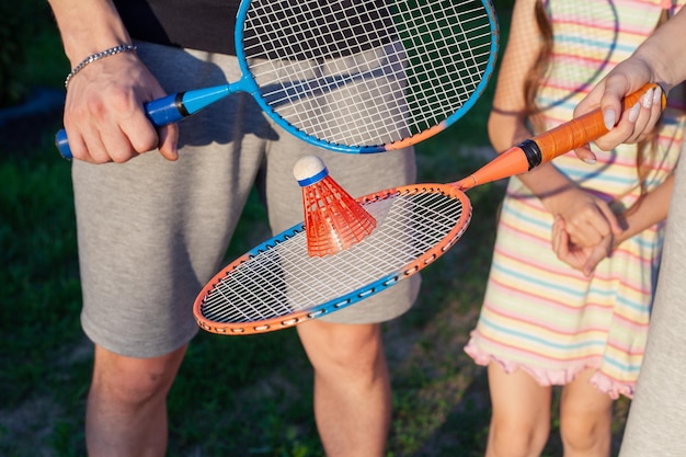 Um cara com uma garota no verão segura raquetes e uma peteca nas mãos