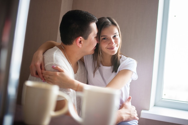 Um cara com uma garota tomando café perto da janela