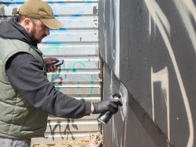 Um cara de boné desenha graffiti o conceito de arte urbana de rua