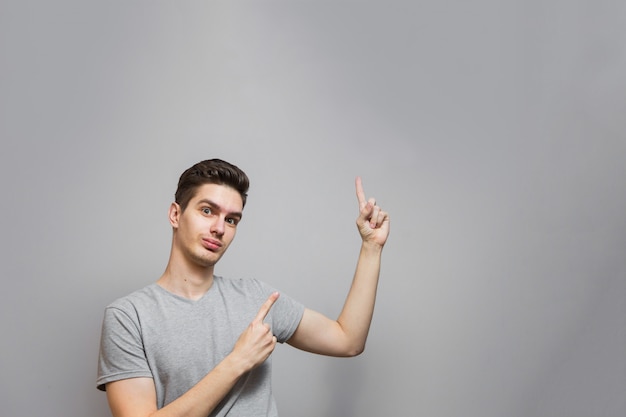 Um cara de camiseta cinza com emoções no rosto.