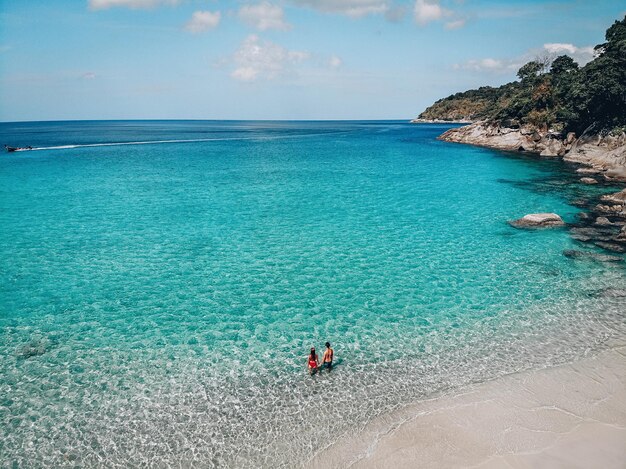 Um cara e uma garota estão em águas claras em uma praia tropical Vista superior