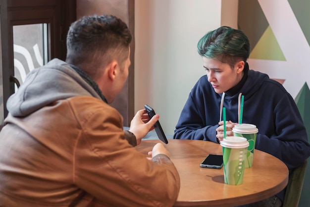 Um cara e uma garota estão sentados em um café e usando smartphones tecnologia de comunicação internet