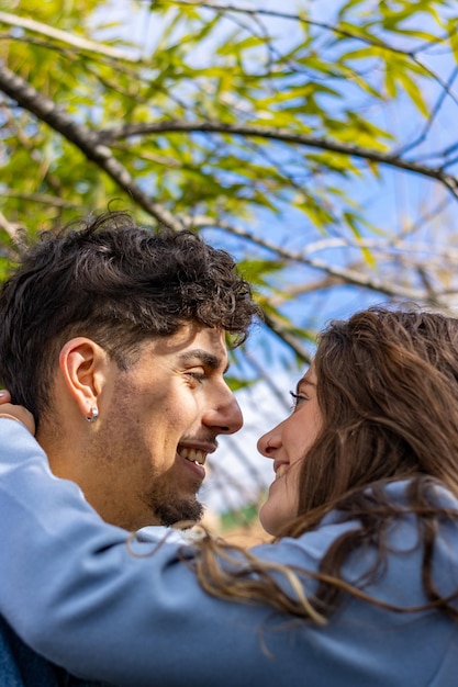 Um cara e uma garota olhando um para o outro no parque Um casal apaixonado sorri e relaxa na natureza Casal heterossexual conceito de relacionamento de amor humano conceito vertical