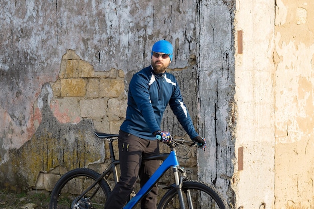 Um cara em roupas esportivas andando em uma bicicleta de montanha moderna em uma parede de concreto de tijolos vintage