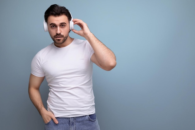 Um cara moreno bonito e brutal em uma camiseta branca com fones de ouvido está dançando