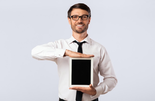 Um cara mostrando uma tela de tablet em branco em uma maquete de fundo branco