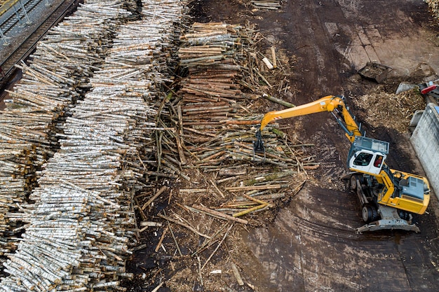 Um carregador carrega toras em uma fábrica de processamento de madeira de cima de um zangão