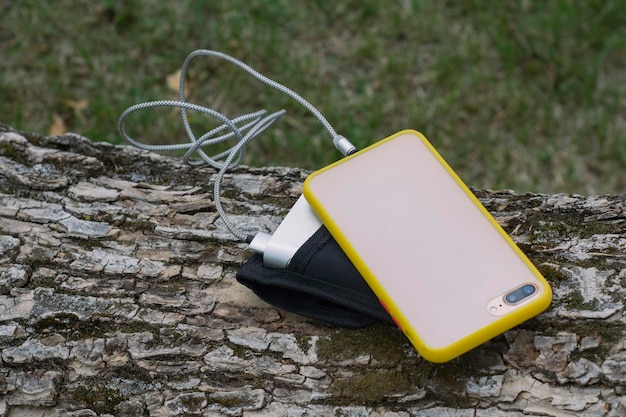 Um carregador portátil carrega o smartphone power bank com cabo contra o fundo de madeira