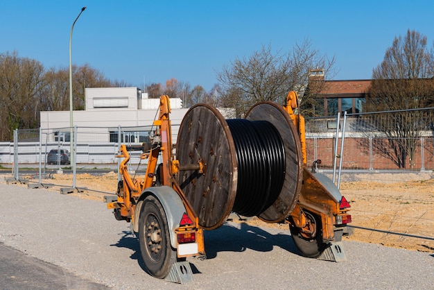 Um carretel de madeira com um cabo elétrico é montado em um canteiro de obras de reboque de duas rodas