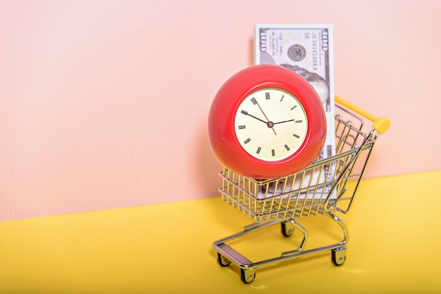 Foto um carrinho de supermercado com antigo despertador vintage em compras de compras de fundo rosa e amarelo