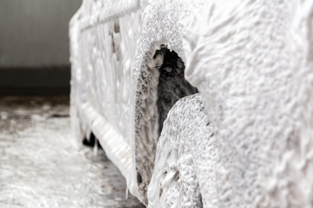 Um carro coberto por espuma de sabão enquanto lavava dentro de casa com foco seletivo