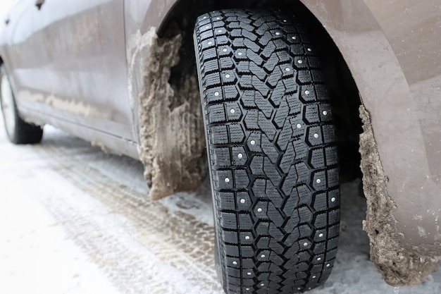 Um carro com pneus de inverno e pontas em uma estrada com neve e granizo