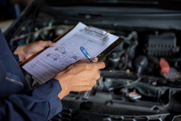 Foto um carro de serviço mecânico na garagem é verificar uma lista de carros.