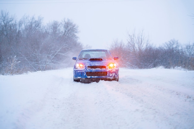 Um carro esporte azul rápido em um dia de inverno com neve, estação fria, estrada de rua