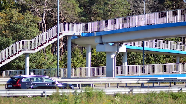 um carro está dirigindo na rodovia com uma ponte ao fundo.