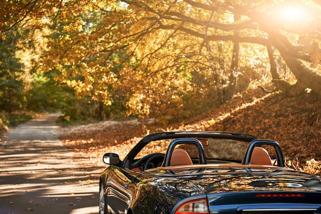 Um carro preto sem teto dirigindo rápido no asfalto com um lindo nascer do sol