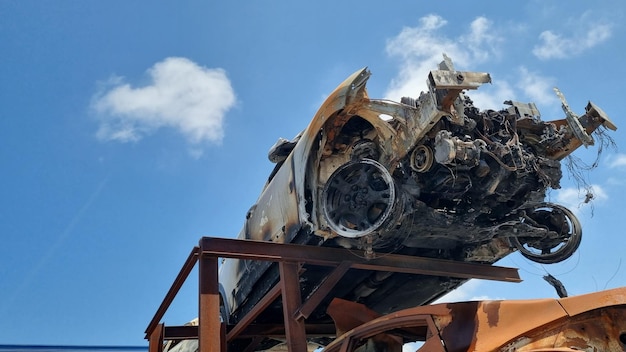 Foto um carro queimado está em uma estrutura de metal.