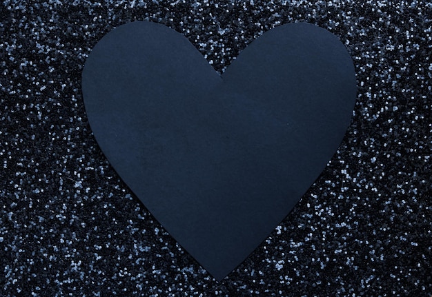 um cartão em forma de coração preto em branco em um fundo brilhante preto