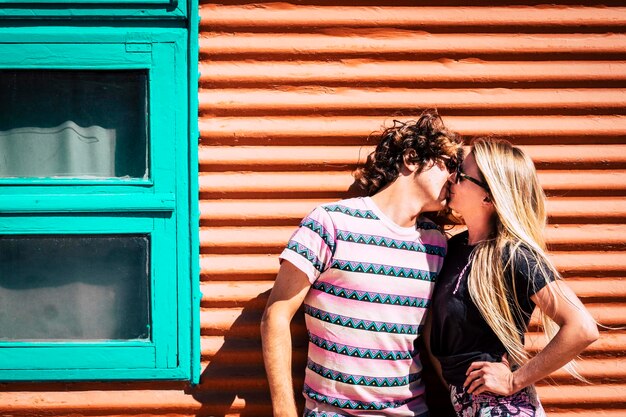Um casal a beijar-se contra a parede junto à janela.