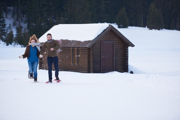 Foto um casal a divertir-se e a andar de sapatos de neve.