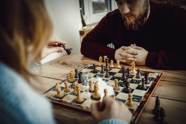 Foto um casal a jogar xadrez na mesa em casa.