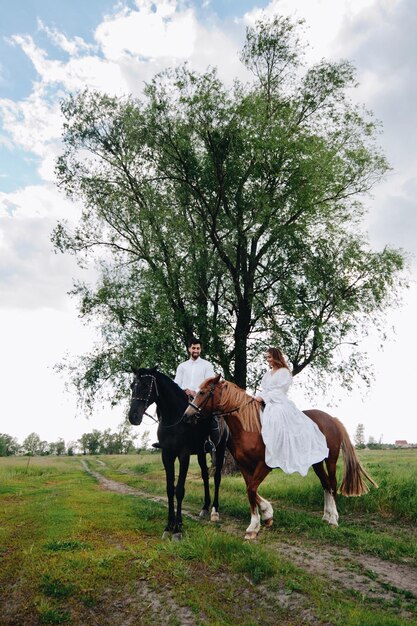 Foto um casal a montar cavalos no campo.