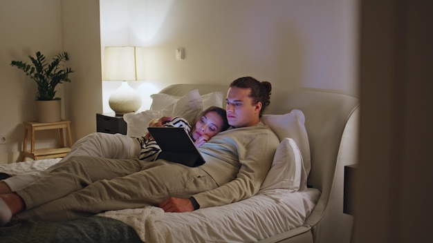 Um casal a passar uma noite aconchegante abraçando a cama a ver o tablet juntos um casal casado