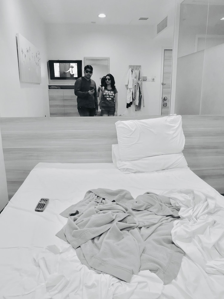 Foto um casal a refletir-se no espelho num quarto de hotel.