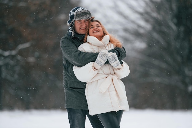 Um casal adorável está juntos a desfrutar de uma caminhada ao ar livre na estação de inverno.