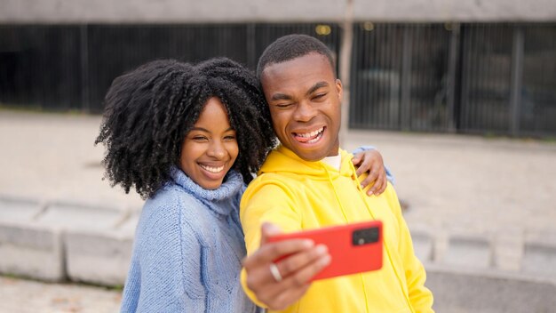 Um casal africano a tirar uma selfie num parque.