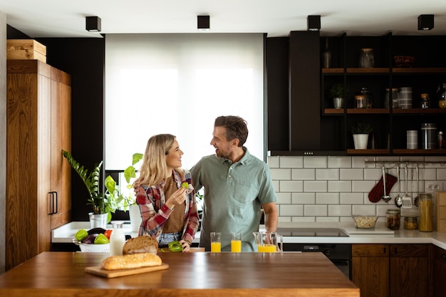 Um casal alegre compartilhando um momento ao pequeno-almoço em uma cozinha moderna