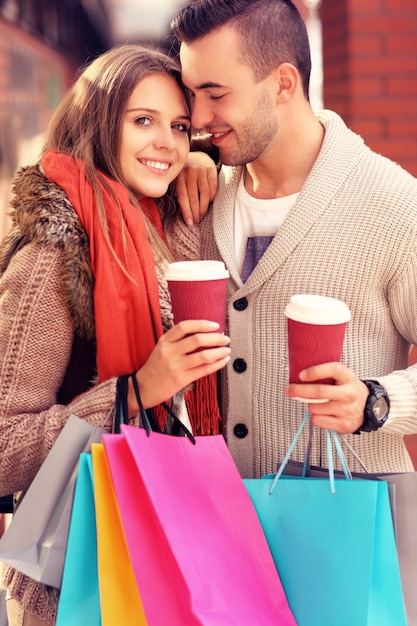 um casal alegre fazendo compras no shopping com café